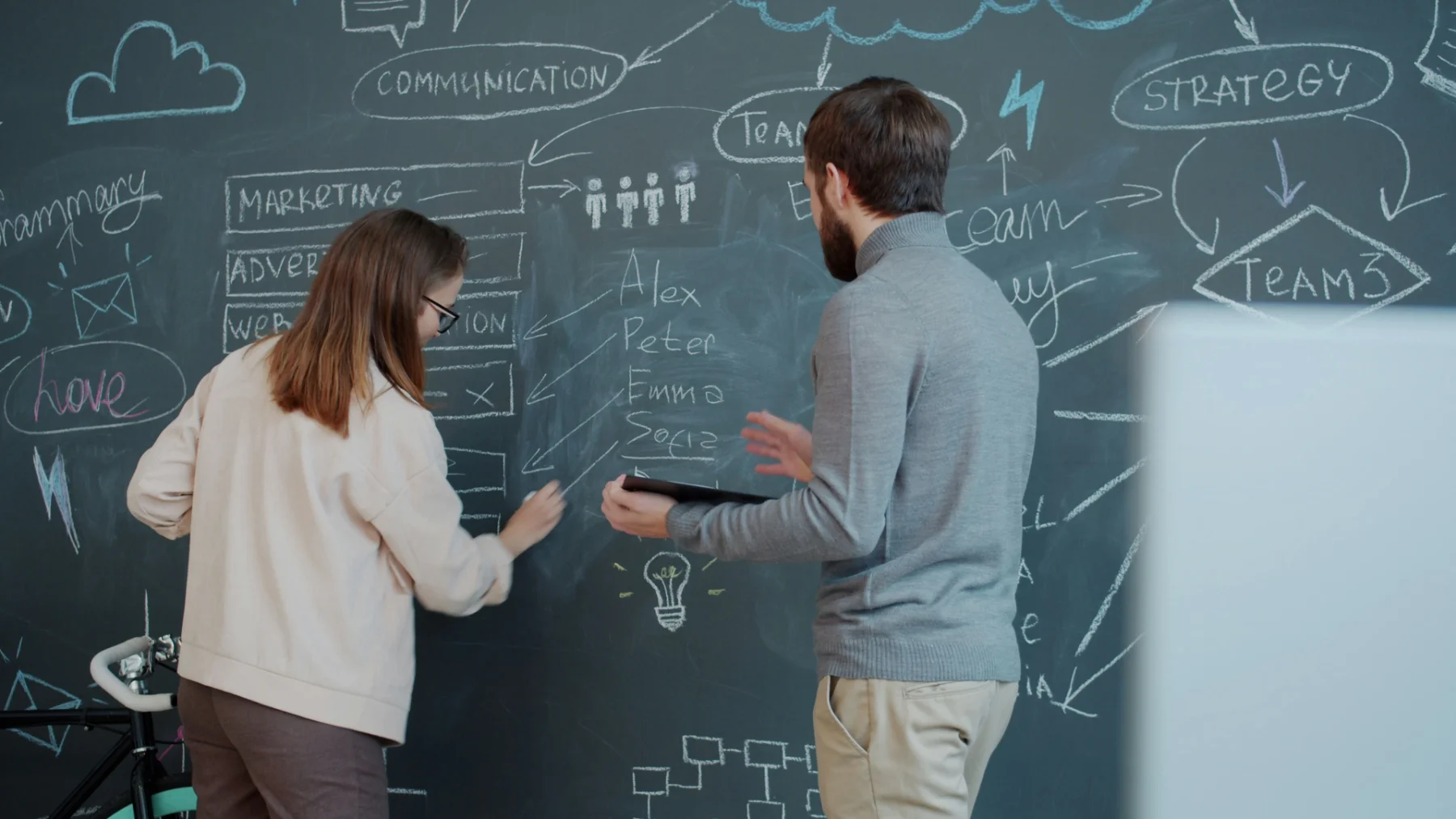 Two people writing on blackboard